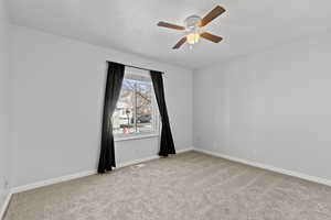 Unfurnished room with light colored carpet, ceiling fan, and a textured ceiling