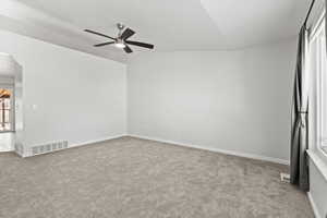 Empty room with vaulted ceiling, a ceiling fan, light carpet, and arched walkways