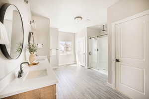 Bathroom with a stall shower, double vanity, and light wood finished floors