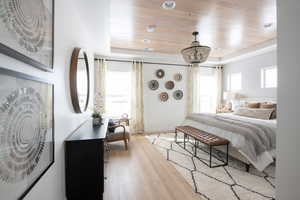 Bedroom with light wood-type flooring and a wooden tray ceiling