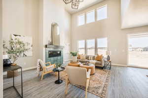 Living room featuring a fireplace, light wood finished floors, and a high ceiling