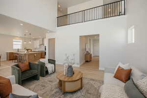 Living room featuring light wood-type flooring, a high ceiling, and recessed lighting