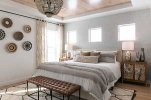 Bedroom with multiple windows, wood finished floors, and a wood tray ceiling