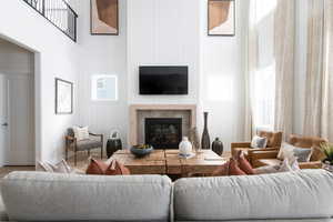 Living area with wood finished floors, a glass covered fireplace, and a high ceiling