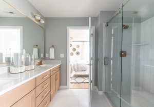 Ensuite bathroom featuring a shower stall, double vanity, and light tile patterned floors
