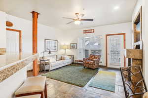 Living area with light stone finish floors and ceiling fan