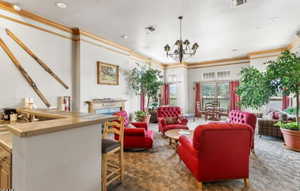 Living room featuring a chandelier, ornamental molding, and dark colored carpet