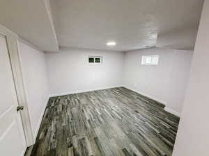 Basement featuring a textured ceiling and dark wood finished floors