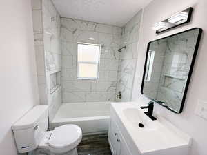 Full bath featuring bathtub / shower combination, vanity, dark wood finished floors, and a textured ceiling