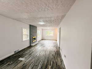 Unfurnished living room with dark wood-style flooring and a brick fireplace