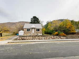 View of front of property with a mountain view, stone siding, an outbuilding, and asphalt driveway