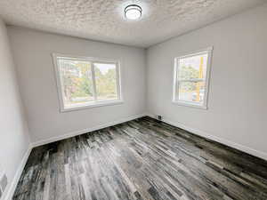 Unfurnished room featuring a textured ceiling and wood finished floors
