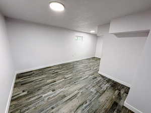 Basement featuring a textured ceiling and dark wood-type flooring