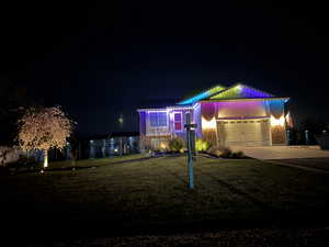View of front of property with a yard, driveway, brick siding, and a garage