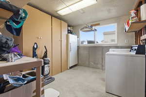 Basement featuring washer / clothes dryer, freestanding refrigerator, and a textured ceiling