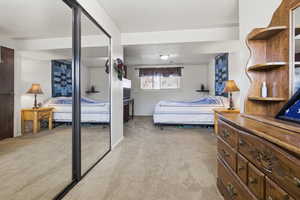 Bedroom featuring a closet, light colored carpet, and a textured ceiling
