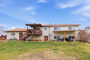 Back of house featuring a lawn, a wooden deck, and a patio
