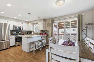 Kitchen with pendant lighting, stainless steel appliances, light stone counters, a peninsula, and white cabinetry