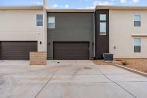 Back of property featuring stucco siding, an attached garage, and concrete driveway
