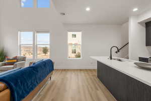 Living room featuring light wood-type flooring, healthy amount of natural light, recessed lighting, and a high ceiling