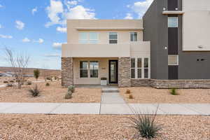 Contemporary home featuring stucco siding, a porch, and stone siding