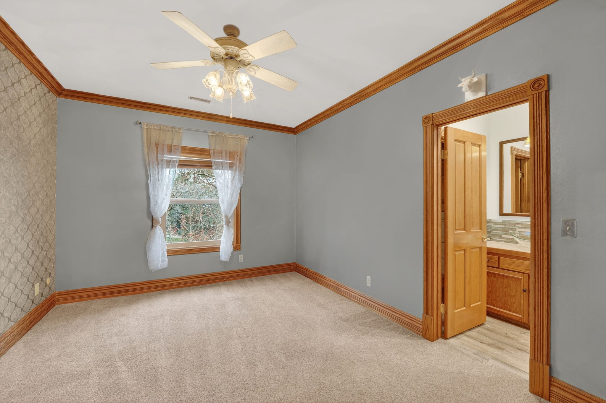 Unfurnished room with wallpapered walls, light colored carpet, a ceiling fan, and crown molding