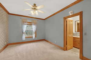 Unfurnished room with wallpapered walls, light colored carpet, a ceiling fan, and crown molding