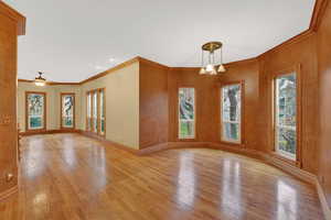 Unfurnished dining area featuring light wood finished floors, ornamental molding, healthy amount of natural light, and a ceiling fan