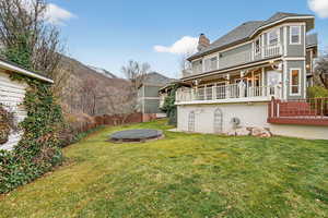 Rear view of house featuring a trampoline, a chimney, and a balcony