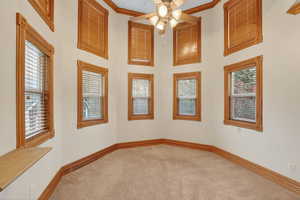 Carpeted spare room with a ceiling fan, a high ceiling, and ornamental molding