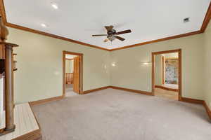 Unfurnished living room featuring light carpet, ornamental molding, and a ceiling fan