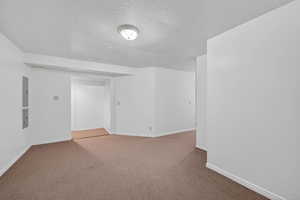 Unfurnished room with a textured ceiling, carpet, and electric panel