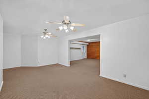 Carpeted spare room with a ceiling fan and baseboards
