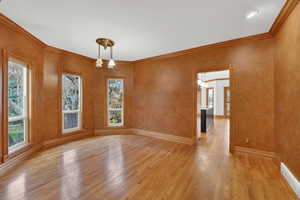 Unfurnished dining area with crown molding, light wood-style flooring, and a chandelier
