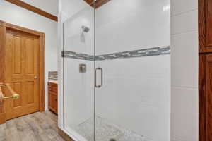Full bath with vanity, a shower stall, light wood-type flooring, and crown molding