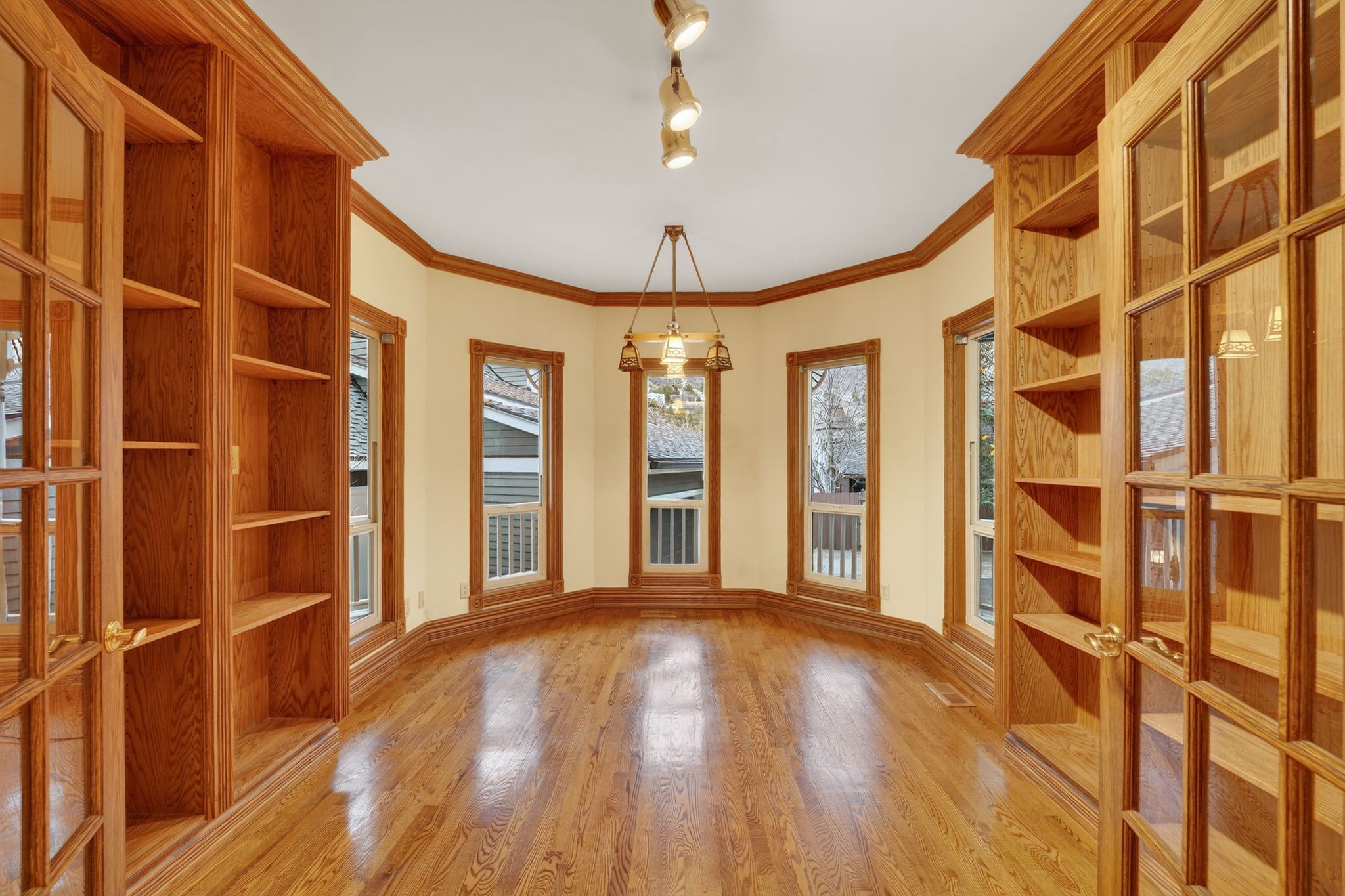 Unfurnished dining area with light wood finished floors, ornamental molding, french doors, and track lighting