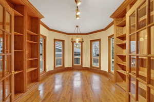Unfurnished dining area with light wood finished floors, ornamental molding, french doors, and track lighting