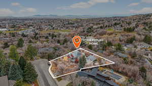 Aerial perspective of suburban area with property parcel outlined and a mountainous background