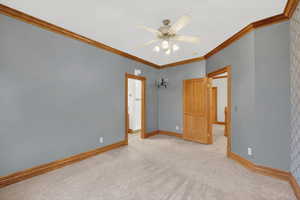 Unfurnished bedroom with crown molding, ceiling fan, and carpet floors