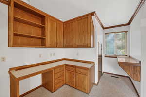 Kitchen featuring open shelves, brown cabinets, built in study area, and crown molding