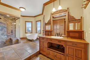 Bathroom with a soaking tub, vanity, a shower stall, ornamental molding, and light tile patterned floors