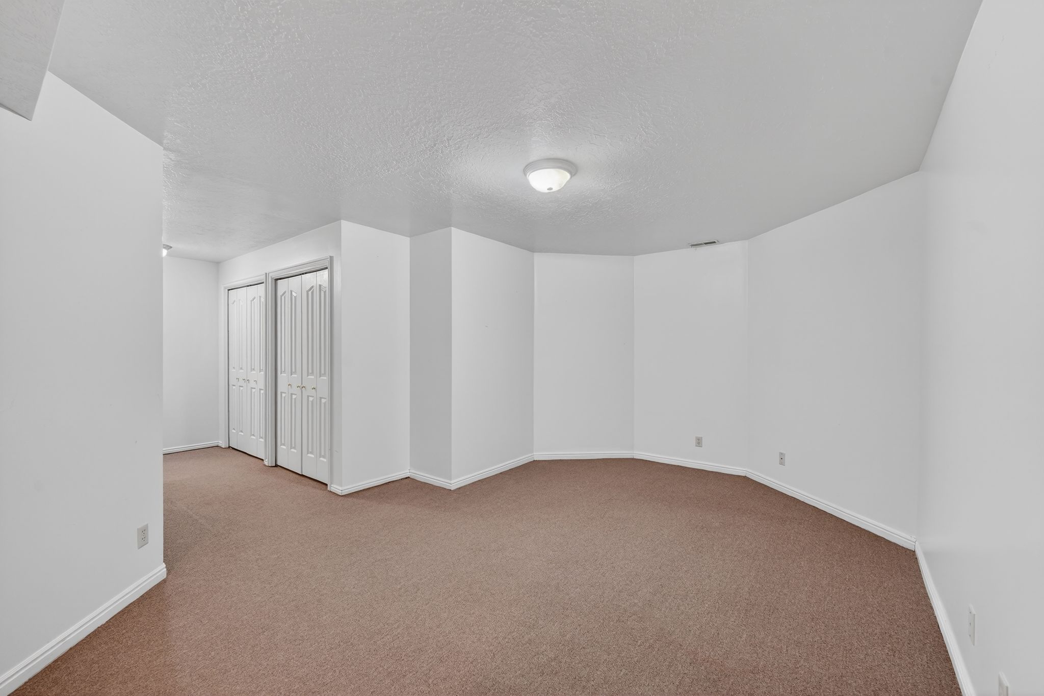 Carpeted spare room featuring a textured ceiling and baseboards