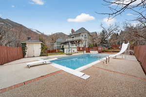 View of pool with a diving board, a fenced backyard, a patio area, and a water slide