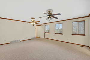 Carpeted empty room featuring ornamental molding and a ceiling fan