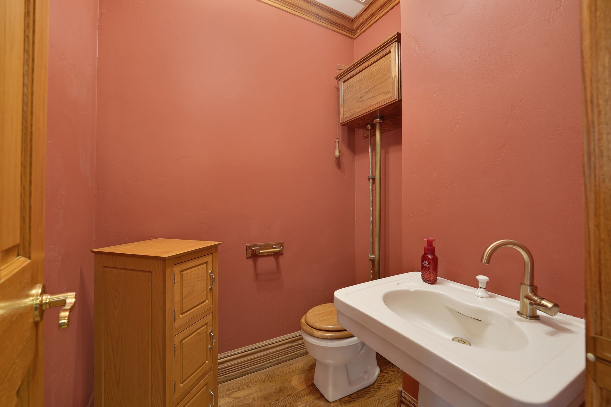 Half bath with ornamental molding and light wood finished floors