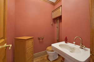 Half bath with ornamental molding and light wood finished floors