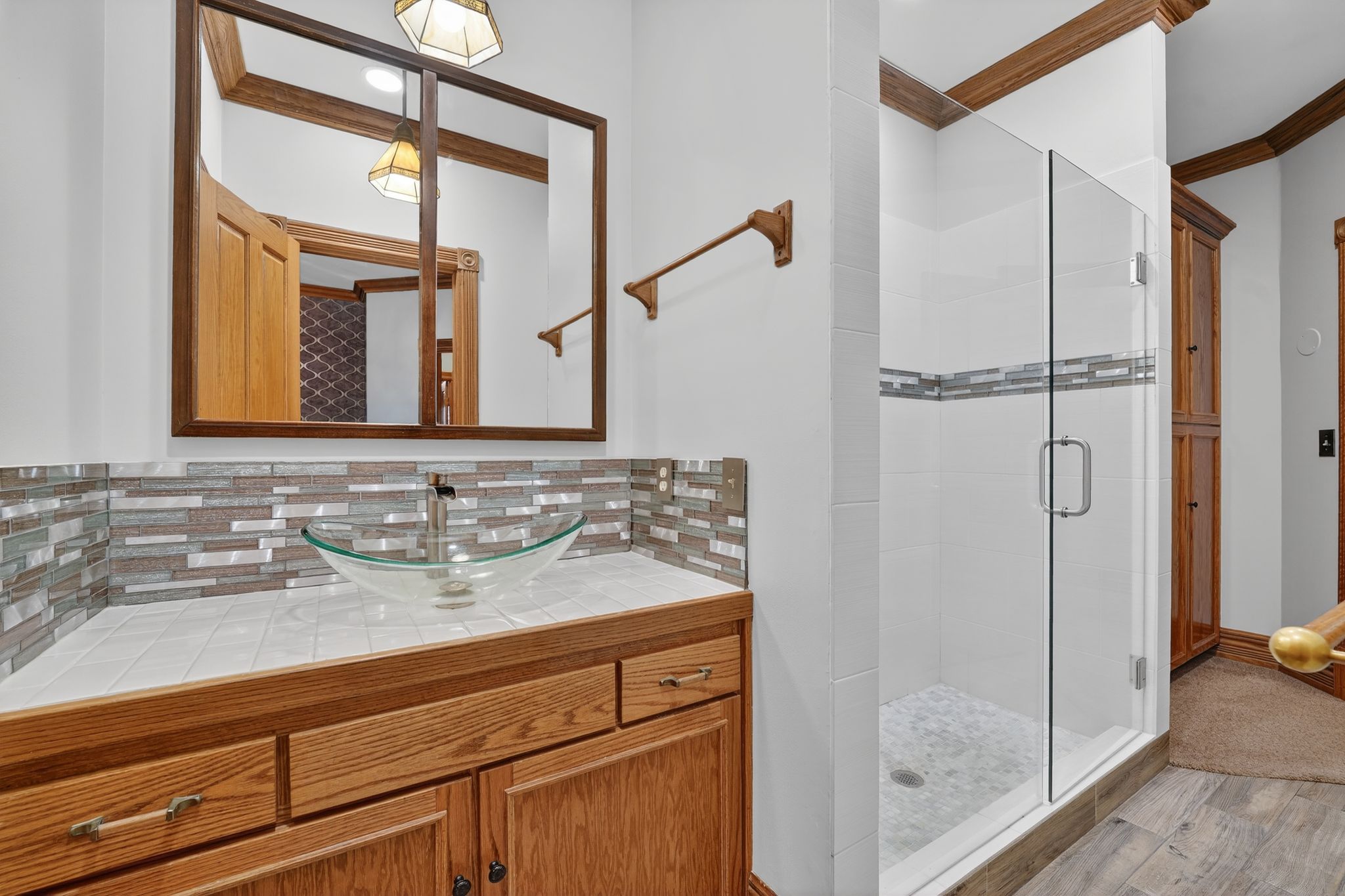 Bathroom featuring ornamental molding, a shower stall, vanity, decorative backsplash, and wood finished floors