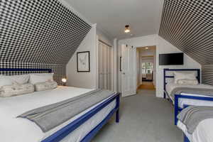 Carpeted bedroom featuring a closet, crown molding, and vaulted ceiling