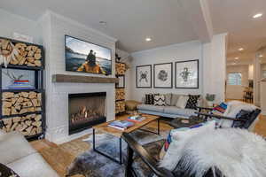 Living area with light wood-style flooring, crown molding, a fireplace, and recessed lighting