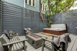 Wooden deck featuring a hot tub and a fire pit